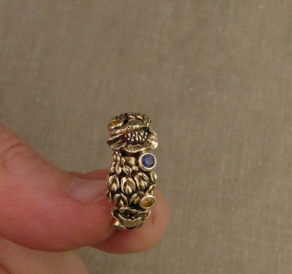 Custom designed & hand-carved California Poppies and Texas Bluebonnets ring in 14K gold with blue sapphires & yellow-orange spessartite garnets. Cheyenne Weil