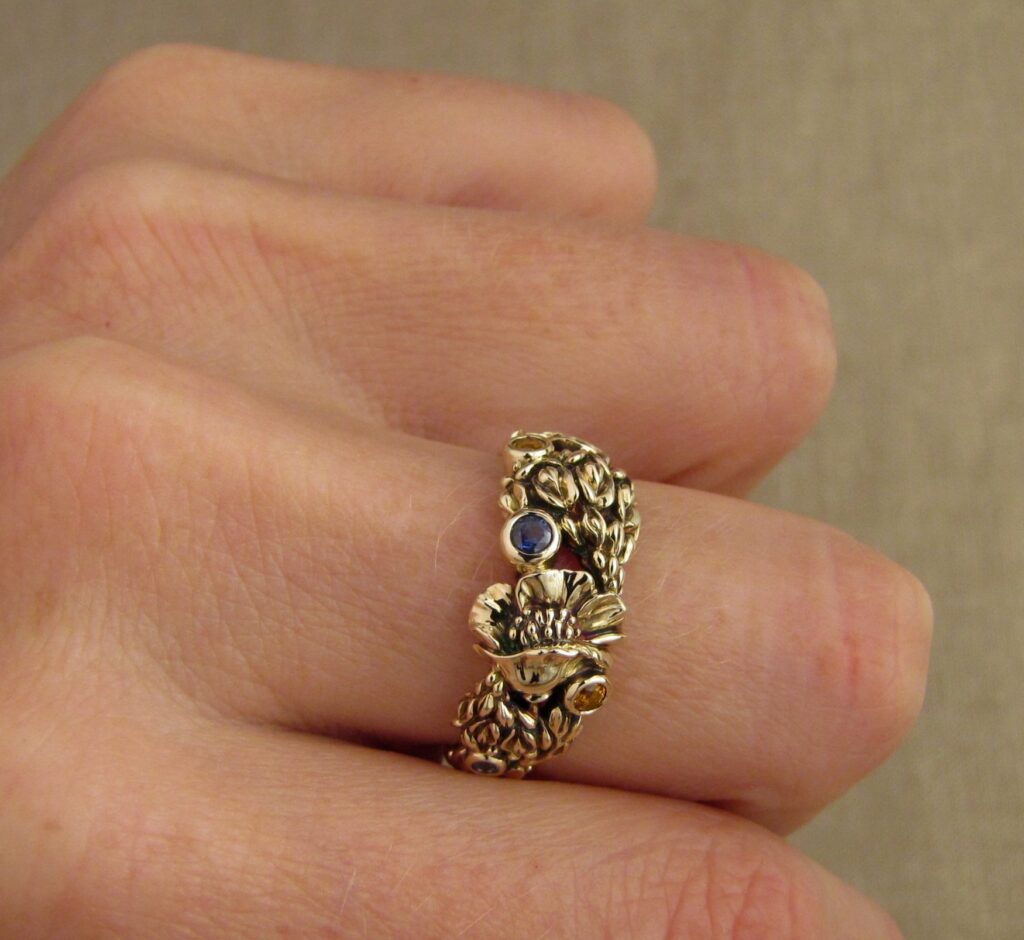 Custom designed & hand-carved California Poppies and Texas Bluebonnets ring in 14K gold with blue sapphires & yellow-orange spessartite garnets. Cheyenne Weil